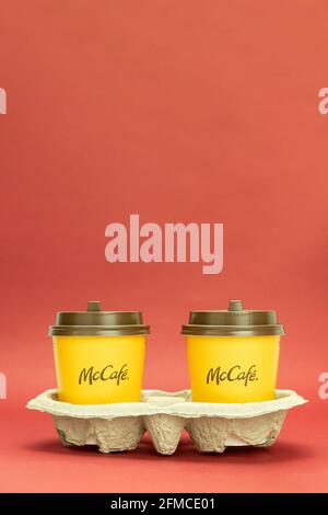 Varsovie, Pologne - 25 mars 2021 : deux tasses de café en papier sur un stand. Deux tasses jetables orange sont dans un tiroir McDonald's marron Banque D'Images