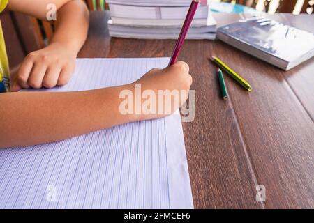 La main de l'élève est écrite sur papier sur la table de l'école. Banque D'Images