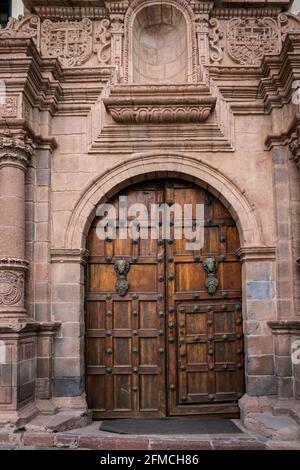 Des portes massives en bois avec intrigue coloniale dominent la scène de rue à Cusco, au Pérou Banque D'Images