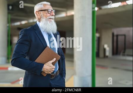 Un homme d'affaires chevronné heureux tient une tablette numérique en attente en ville gare routière Banque D'Images