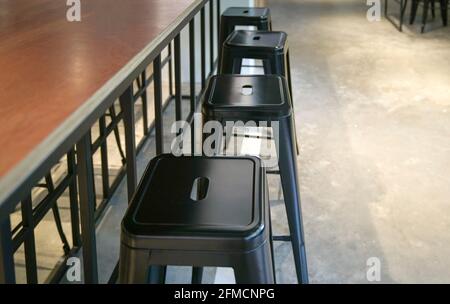 Rangée de tabourets en métal noir à côté d'une table en bois dans un restaurant. Copier l'espace. Banque D'Images