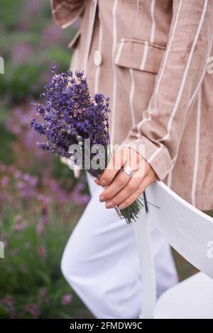 gros plan sur le bouquet de fleurs de lavande en main de femme dans les champs de prés. photo de faible profondeur de champ Banque D'Images