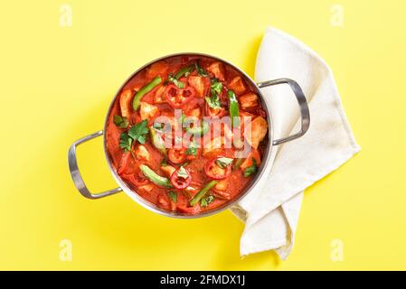 Curry de poulet rouge de style thaïlandais avec légumes dans une casserole sur fond jaune. Vue de dessus, plan d'appartement Banque D'Images