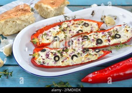 Cuisine méditerranéenne - poivrons rouges pointus cuits, remplis de feta grecque et de fromage à la crème de chèvre, d'oignons, de poireaux, d'herbes et d'olives noires Banque D'Images