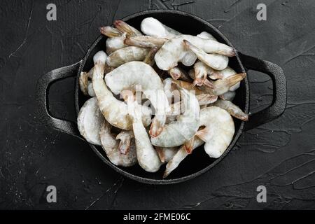 Carapace surgelée sur crevettes tigrées ou crevettes tigrées asiatiques, dans une poêle à frire en fonte, sur fond de pierre noire, vue du dessus à plat Banque D'Images