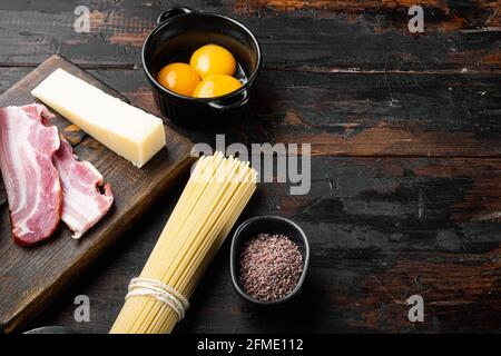 Ingrédients pour faire des pâtes alla carbonara prosciutto, ensemble de pâtes crues, sur une ancienne table en bois sombre, avec espace pour le texte Banque D'Images