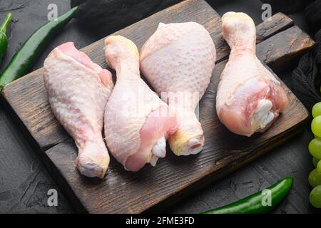 Ensemble de cuisses de poulet frais et d'ingrédients de marinade, sur planche à découper en bois, sur fond de pierre noire Banque D'Images