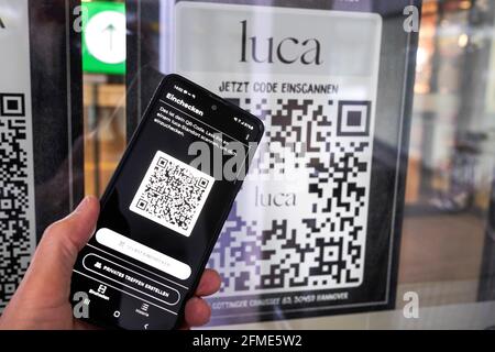 L'application Luca sur un smartphone scanne un code QR Luca à l'entrée d'un marché alimentaire à Hanovre. Vous pouvez enregistrer et sortir avec votre téléphone mobile et cela permet de tracer les chaînes d'infection de corona. Hanovre, Allemagne, le 8 mai 2021 --- Luca-App auf einem smartphone scannt einen Luca QR-Code Am Eingang eines Lebensmittelmarktes à Hanovre. Betrieb einer Bürgen und Verkauf von Dienstleistungen. Hanovre, 8.5.2021 Banque D'Images