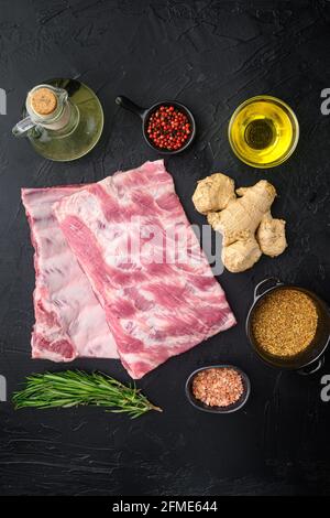 Viande de porc fraîche crue de ferme biologique avec épices, avec miel, sur fond de pierre noire, plan de dessus de lit Banque D'Images