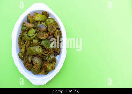 Délicieux cari au poivron vert ou au poivron vert. Remuez avec des oignons sautés sabaji asiatique indien avec du masala. Sur fond rouge, l'image de la nourriture est un espace de copie de Banque D'Images