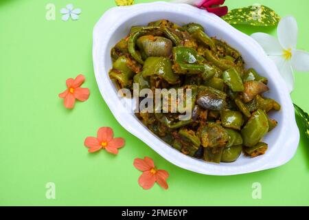 Délicieux cari au poivron vert ou au poivron vert. Remuez avec des oignons sautés sabaji asiatique indien avec du masala. Sur fond rouge, l'image de la nourriture est un espace de copie de Banque D'Images