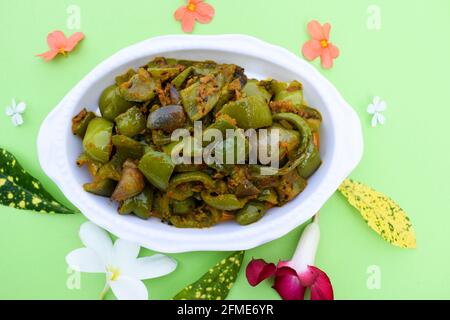 Délicieux cari au poivron vert ou au poivron vert. Remuez avec des oignons sautés sabaji asiatique indien avec du masala. Sur fond rouge, l'image de la nourriture est un espace de copie de Banque D'Images