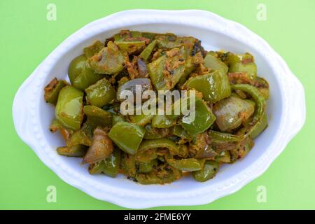 Délicieux cari au poivron vert ou au poivron vert. Remuez avec des oignons sautés sabaji asiatique indien avec du masala. Sur fond rouge, l'image de la nourriture est un espace de copie de Banque D'Images