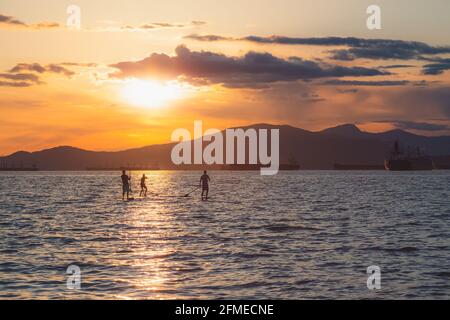 Silhouette de paddle-boarders au coucher du soleil lumière de l'heure d'or Sur l'eau de l'océan Pacifique ouvert à Kitsilano Beach sur an Soirée d'été idyllique à Vancou Banque D'Images