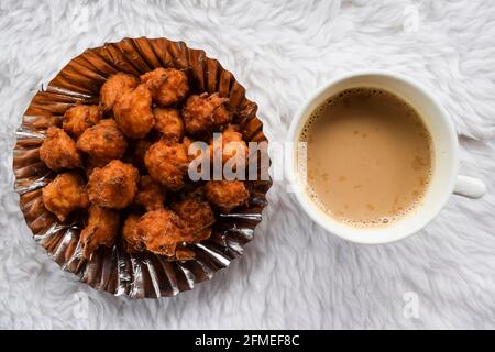 Bhajiya ou Pakoda de riz savoureux, également connu sous le nom de beignets de boule de riz, est fait de reste de riz, de farine de gramme servi dans l'assiette avec une tasse chaude de masala t indien Banque D'Images