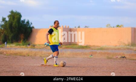 Marrakech, Maroc - 25 AVRIL 2021 : hommes jouant au football sur un terrain poussiéreux Marrakech au Maroc Banque D'Images