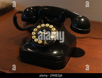 Un ancien téléphone à bouton-poussoir rotatif noir est installé un comptoir en bois Banque D'Images