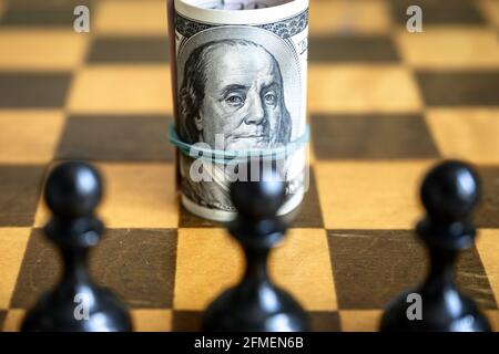 Dollar avec Franklin contre les chiffres des échecs, argent américain sur chessboard en bois. Symbole de la finance et jeu d'échecs. Concept de la stratégie monétaire, investissement, u Banque D'Images