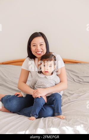 Femme asiatique chinoise qui s'embrasse au lit avec une petite fille à la maison. Fille fille enfant avec maman ensemble. Une mère qui s'embrasse avec une petite fille. ETH Banque D'Images