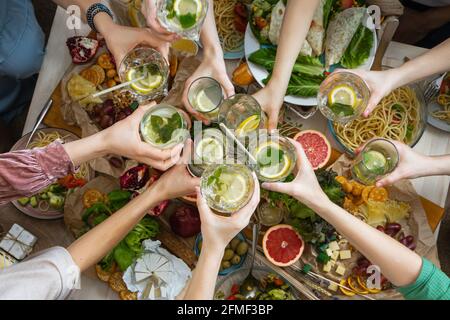 Vue de dessus gros plan femelles amis mains cheers toaster verre de boisson saine sur table de service Banque D'Images