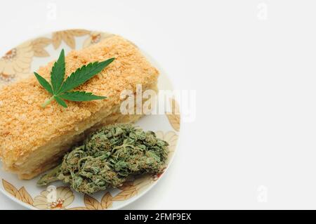 Gâteau de bouffée avec de l'huile de CBD et des fleurs de cannabis isolées sur fond blanc. La cuisine de marijuana, délicieux dessert fait maison. Banque D'Images