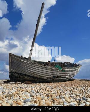 Bateau en bois abandonné en décomposition sur la plage de galets avec espace de copie. Banque D'Images