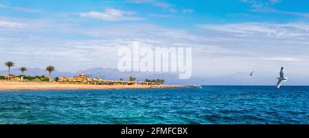 Paysage de la côte de la mer Rouge près de la station de Dahab en Egypte avec silhouettes de montagnes de Jordanie à l'horizon. Banque D'Images