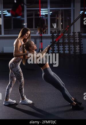 La fille fait des exercices avec l'équipement. Une femme dans la salle de gym pour l'entraînement circulaire est engagée dans des boucles sous la supervision d'un entraîneur. Femme Banque D'Images