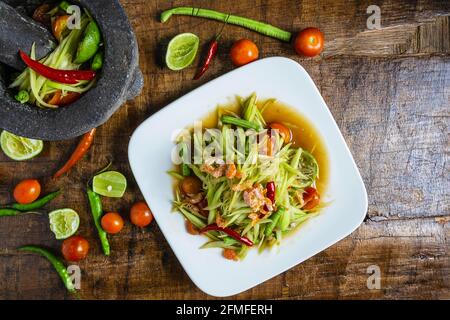 Cuisine thaïlandaise, salade de papaye et salade de papaye dans un plat avec une portion sur une table en bois. Banque D'Images