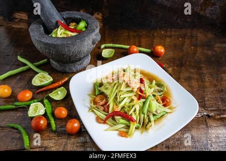 Cuisine thaïlandaise, salade de papaye et salade de papaye dans un plat avec une portion sur une table en bois. Banque D'Images