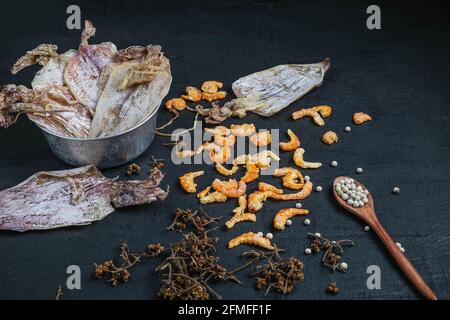 Fruits de mer séchés avec calmar et crevettes séchées sur un table en bois noir Banque D'Images