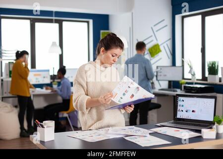 La staticienne concentrée étudie les statistiques, lit les données d'information contenant des documents administratifs. Entrepreneur exécutif, chef d'équipe cadre travaillant sur des projets avec divers collègues. Banque D'Images