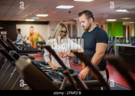 Fréquence cardiaque le médecin mesure le pouls pendant un test d'effort. Un médecin féminin mesure le rythme cardiaque d'un athlète masculin pendant Banque D'Images