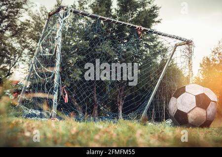 Ancienne porte de football libre ou porte de but de football négligée sur terrain de pelouse rural, vue latérale. Terrain de sport avec but rouillé et filet, extérieur avec lumineux s Banque D'Images