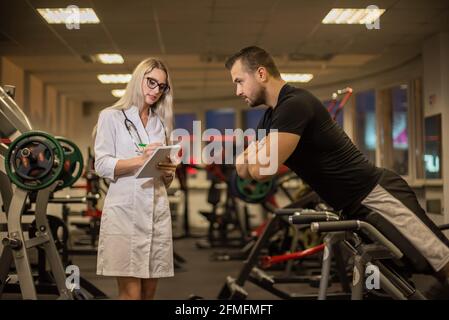 Fréquence cardiaque le médecin mesure le pouls pendant un test d'effort. Un médecin féminin mesure le rythme cardiaque d'un athlète masculin pendant Banque D'Images