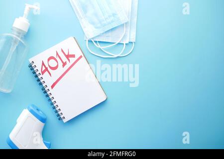 Bloc-notes avec mot écrit à la main 401k , masque, assainisseur sur bleu Banque D'Images