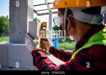 Outil de construction de briques en gros plan à l'aide du niveau d'eau, vérifiez l'inclinaison des blocs de béton cellulaire autoclavés. Mural, installation de briques sur l'interprétation Banque D'Images