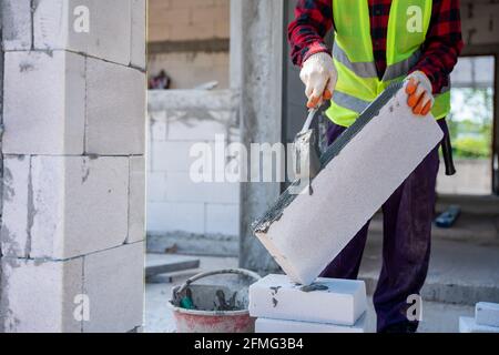 Gros plan du constructeur de briques en utilisant le mortier de ciment pour mettre les briques légères. Sur le chantier Banque D'Images