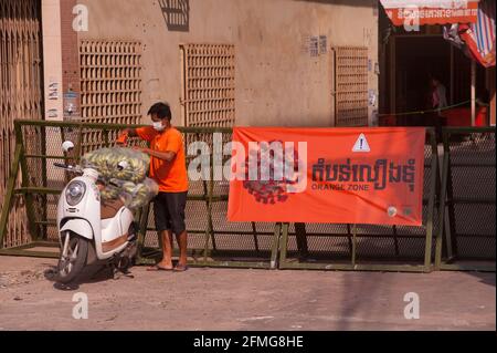 Phnom Penh, Cambodge. 9 mai 2021. Un cambodgien fait de son mieux pour faire savoir qu'il livrait des bananes depuis une zone Orange, portant un T-shirt orange et utilisant de la bande orange. Après 3 semaines de confinement total, le gouvernement a divisé Phnom Penh en 3 zones de couleur (Rouge, orange et jaune) en raison de l'augmentation continue de COVID - 19. Ici, un poste de contrôle de la police à l'entrée d'une « zone Orange », ce qui signifie un risque moyen d'infection. Credit: Kraig Lieb / Alay Live News Banque D'Images