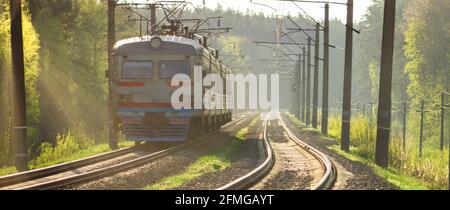 Train sur les voies ferrées. Voies de circulation des trains. Lumière du soleil et lustre métallique. Banque D'Images