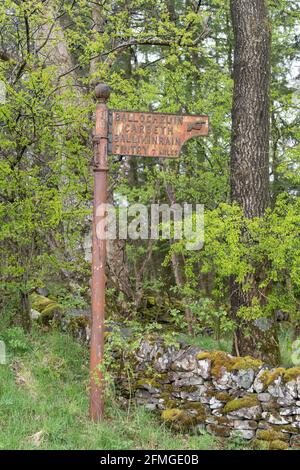 Vieux panneau de route rouillé avec le doigt pointant - Ballochruin, Carbeth, Ballikinrain, Fintry à la gare de Balfron, Stirling, Écosse, Royaume-Uni Banque D'Images