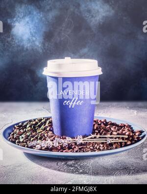 Composition de café floue verticale avec une tasse de café à emporter de latte de lavande chaude avec de la vapeur sur des grains de café sur un fond bleu foncé. Le concept de Banque D'Images