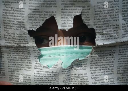 Une femme portant un masque avec un journal déchiré dedans avant Banque D'Images