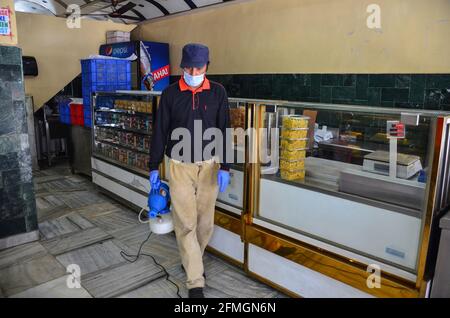 Srinagar, Inde. 09e mai 2021. Un travailleur portant un masque désinfecte la boulangerie avant le festival musulman Eid al-Fitr lors d'un confinement imposé par les autorités à la suite de l'augmentation des cas de coronavirus à Srinagar. Alors que le mortel Covid-19 continue de menacer la vallée, les autorités ont prolongé dimanche le confinement actuel du COVID-19 devant le festival musulman Eid al-Fitr. Crédit : SOPA Images Limited/Alamy Live News Banque D'Images