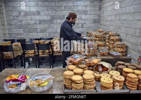 Srinagar, Inde. 09e mai 2021. Un travailleur portant un masque facial arrange des articles de boulangerie à l'intérieur d'un magasin avant le festival musulman Eid al-Fitr lors d'un confinement imposé par les autorités suite à l'augmentation des cas de coronavirus à Srinagar. Alors que le mortel Covid-19 continue de menacer la vallée, les autorités ont prolongé dimanche le confinement actuel du COVID-19 devant le festival musulman Eid al-Fitr. Crédit : SOPA Images Limited/Alamy Live News Banque D'Images