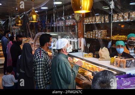 Srinagar, Inde. 09e mai 2021. Les résidents portant des masques faciaux font leurs courses dans une boulangerie avant le festival musulman Eid al-Fitr lors d'un confinement imposé par les autorités suite à l'augmentation des cas de coronavirus à Srinagar. Alors que le mortel Covid-19 continue de menacer la vallée, les autorités ont prolongé dimanche le confinement actuel du COVID-19 devant le festival musulman Eid al-Fitr. Crédit : SOPA Images Limited/Alamy Live News Banque D'Images