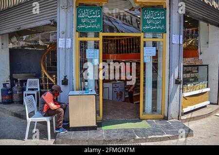 Srinagar, Inde. 09e mai 2021. Un travailleur attend de désinfecter ses clients à l'extérieur d'un magasin de boulangerie avant le festival musulman Eid al-Fitr lors d'un confinement imposé par les autorités suite à l'augmentation des cas de coronavirus à Srinagar. Alors que le mortel Covid-19 continue de menacer la vallée, les autorités ont prolongé dimanche le confinement actuel du COVID-19 devant le festival musulman Eid al-Fitr. Crédit : SOPA Images Limited/Alamy Live News Banque D'Images