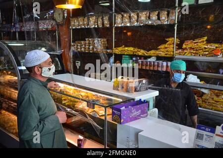 Srinagar, Inde. 09e mai 2021. Un résident portant un masque facial dans un magasin de boulangerie avant le festival musulman Eid al-Fitr lors d'un confinement imposé par les autorités suite à l'augmentation des cas de coronavirus à Srinagar. Alors que le mortel Covid-19 continue de menacer la vallée, les autorités ont prolongé dimanche le confinement actuel du COVID-19 devant le festival musulman Eid al-Fitr. (Photo de Saqib Majeed/SOPA Images/Sipa USA) crédit: SIPA USA/Alay Live News Banque D'Images