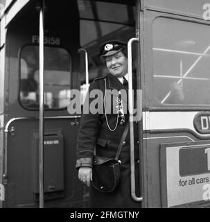 Années 1960, historique, un chef d'autobus féminin debout à l'entrée arrière, près de l'escalier, d'un autobus routemaster à impériale, Écosse, Royaume-Uni. Ces dames étaient connues sous le nom de « clippies » pendant la Seconde Guerre mondiale en raison de leurs machines à billets qui « clippaient » les billets. Les conducteurs, à la fois femelles et mâles, étaient une partie essentielle du fonctionnement d'un bus à impériale étant à l'extrémité opposée du conducteur qui était dans une cabine scellée. Banque D'Images