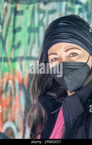 Portrait d'une jolie femme d'âge moyen de 50 ans avec des cheveux gris et masque de protection avec un mur de graffiti dans le arrière-plan Banque D'Images